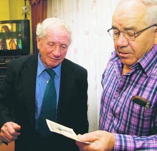 Juan Manuel Moro -izquierda- y Avelino Pérez miran fotografías antiguas en Riaño. 